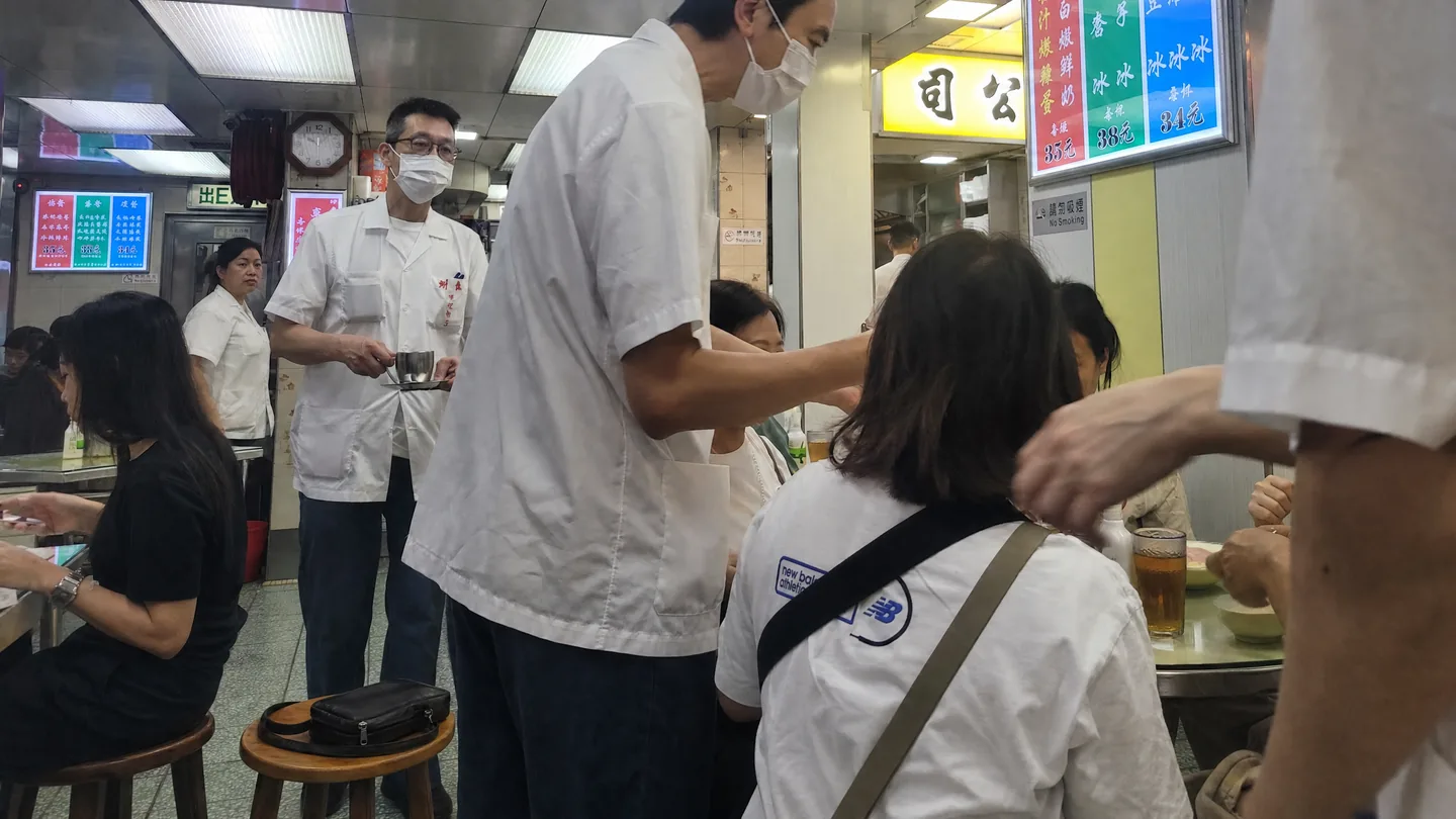 澳洲牛奶公司內，黑色手袋安放在木凳上，侍應從旁走過。