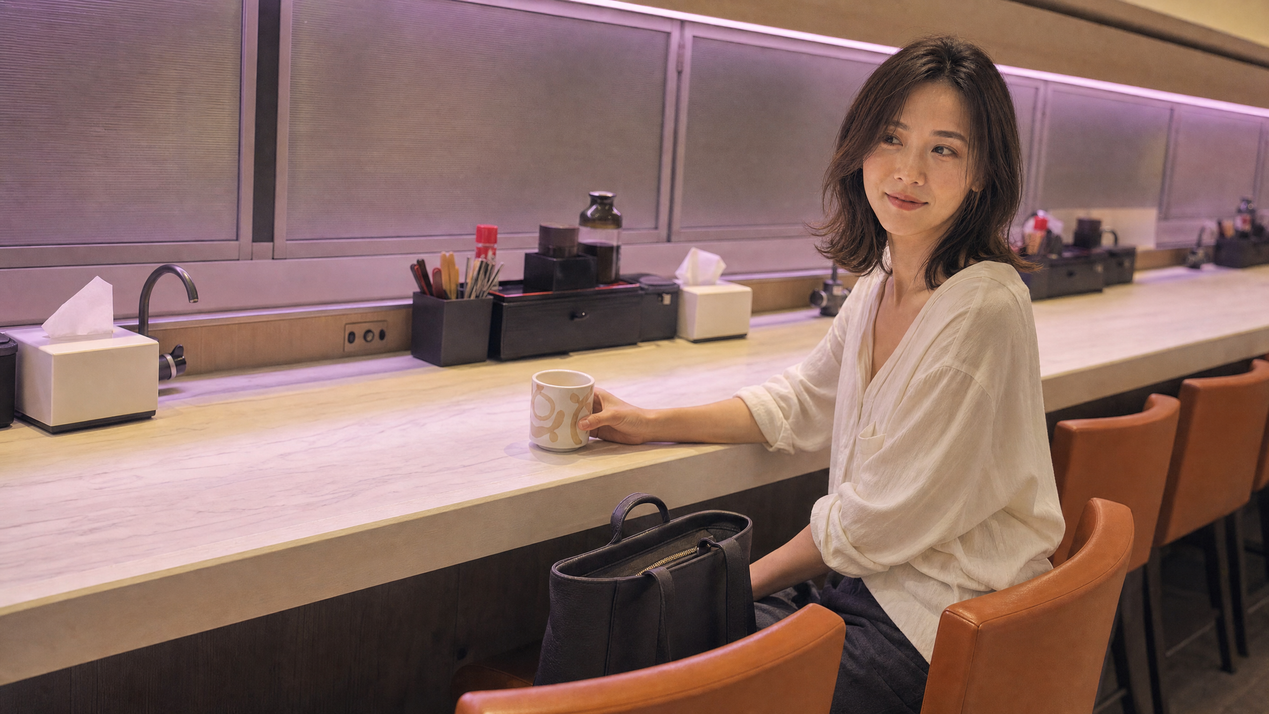 Solene 坐在元氣壽司的吧座旁,手袋放在獲預留的椅子上。